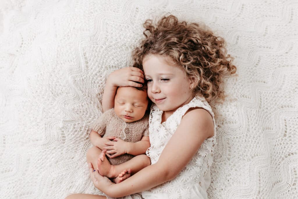 Newbornshooting mit Geschwister liegend in weiß mit schönem Haarband bei Conni Breyer Fotografie am Bodensee nähe Konstanz