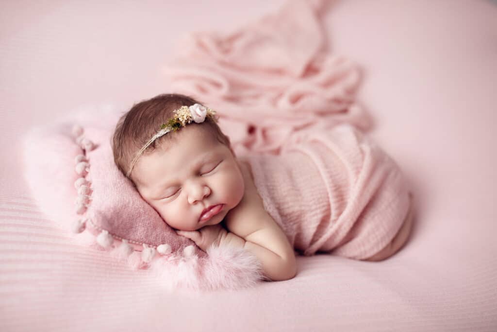 Süßes Baby in rosa auf Kissen und Haarband schlafend bei conni breyer fotografie nähe Ravensburg