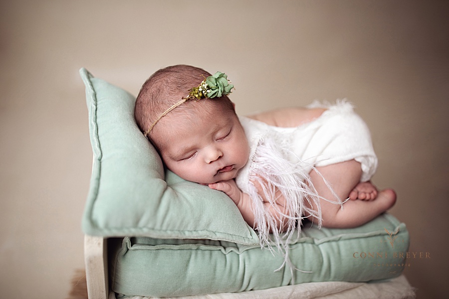 Süßes Neugeborenes auf Samtkissen in einem kleinen Bett auf Samtmatratze in mintgrün bei Conni Breyer fotografie nähe Bregenz