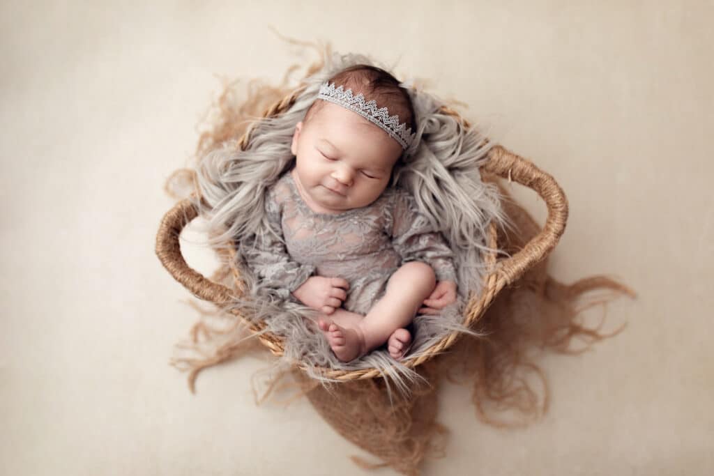 Süßes neugeborenes Baby Mädchen in grau mit süßem Haarband in Korb bei conni breyer Fotografie nähe Konstanz