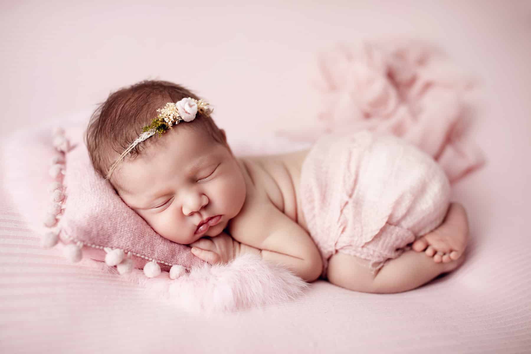 Baby schlafend in rosa mit Haarband mit Kissen und Fell bei conni breyer Fotografie nähe Vorarlberg