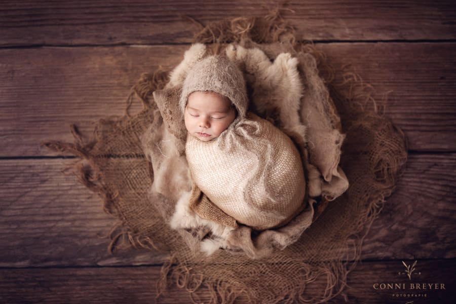 Süßes Babyfoto mit Mütze in Holzschale am Bodensee nähe Bregenz - Conni Breyer Fotografin