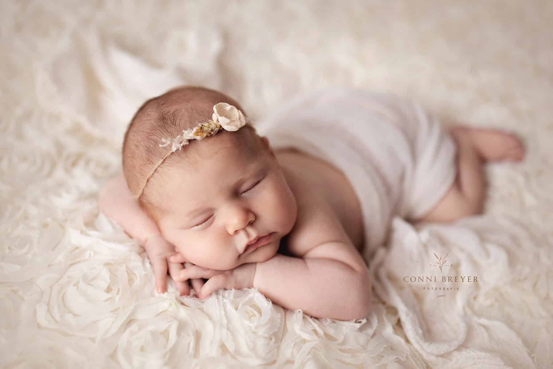 Süßes neugeborenes Baby in creme mit süßem Blumen Haarband bei conni breyer Fotografie nähe Überlingen