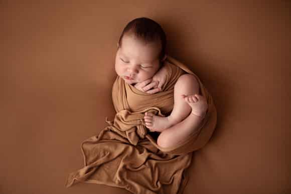 Babybilder eines kleinen Jungen in herbstlichen Farben in Tuch gewrappt bei Conni Breyer Fotografie am Bodensee